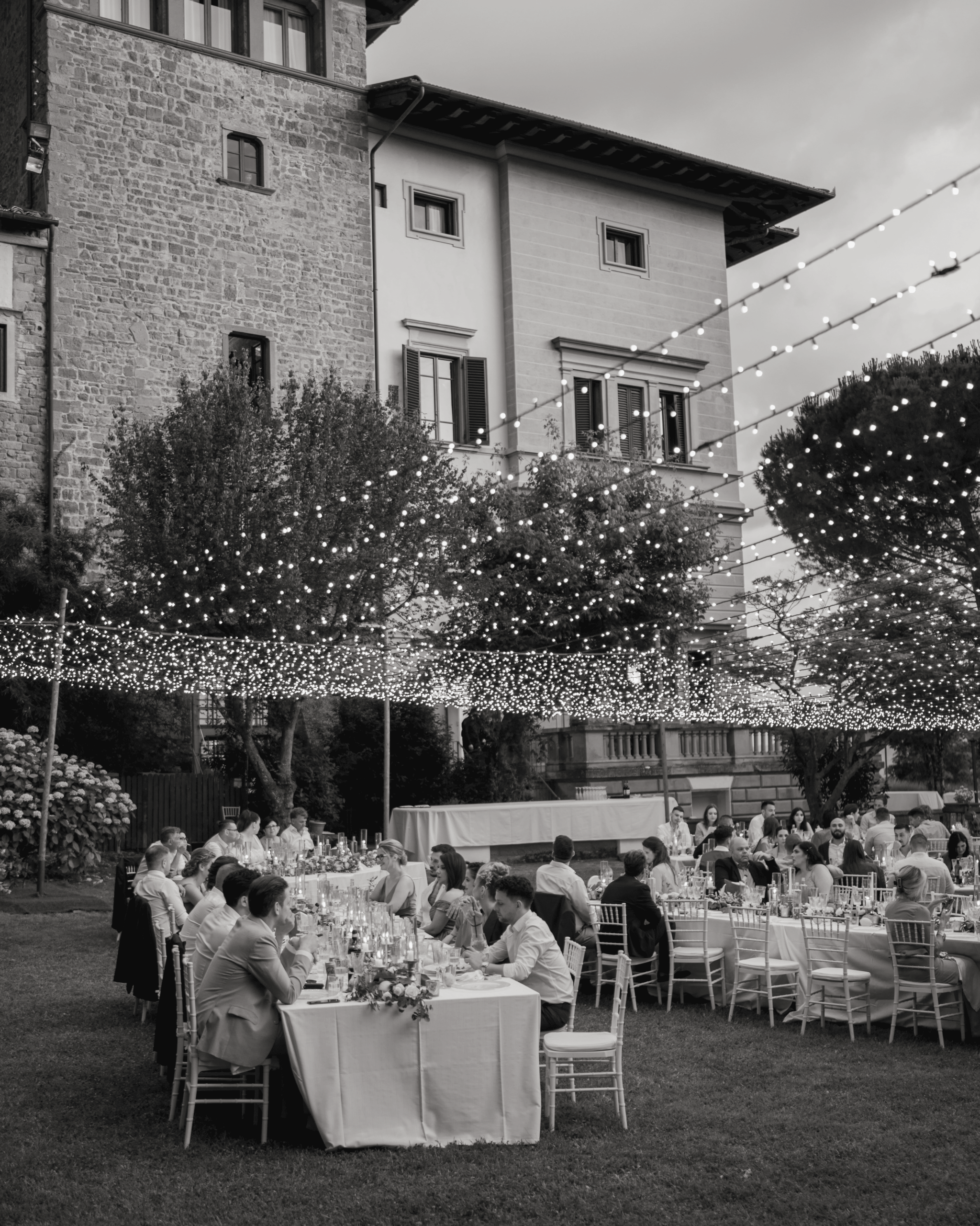 Elegant outdoor wedding dinner with fairy lights in front of historic villa