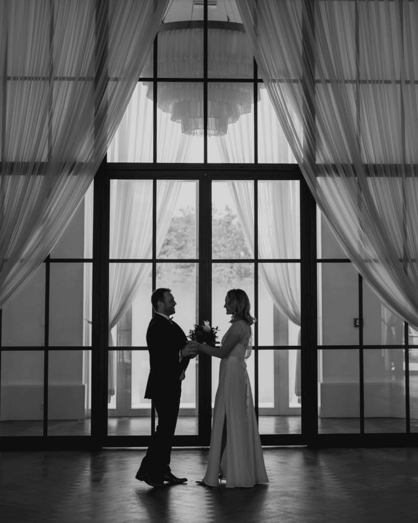 Silhouette of a bride and groom in an elegant wedding hall in front of large windows