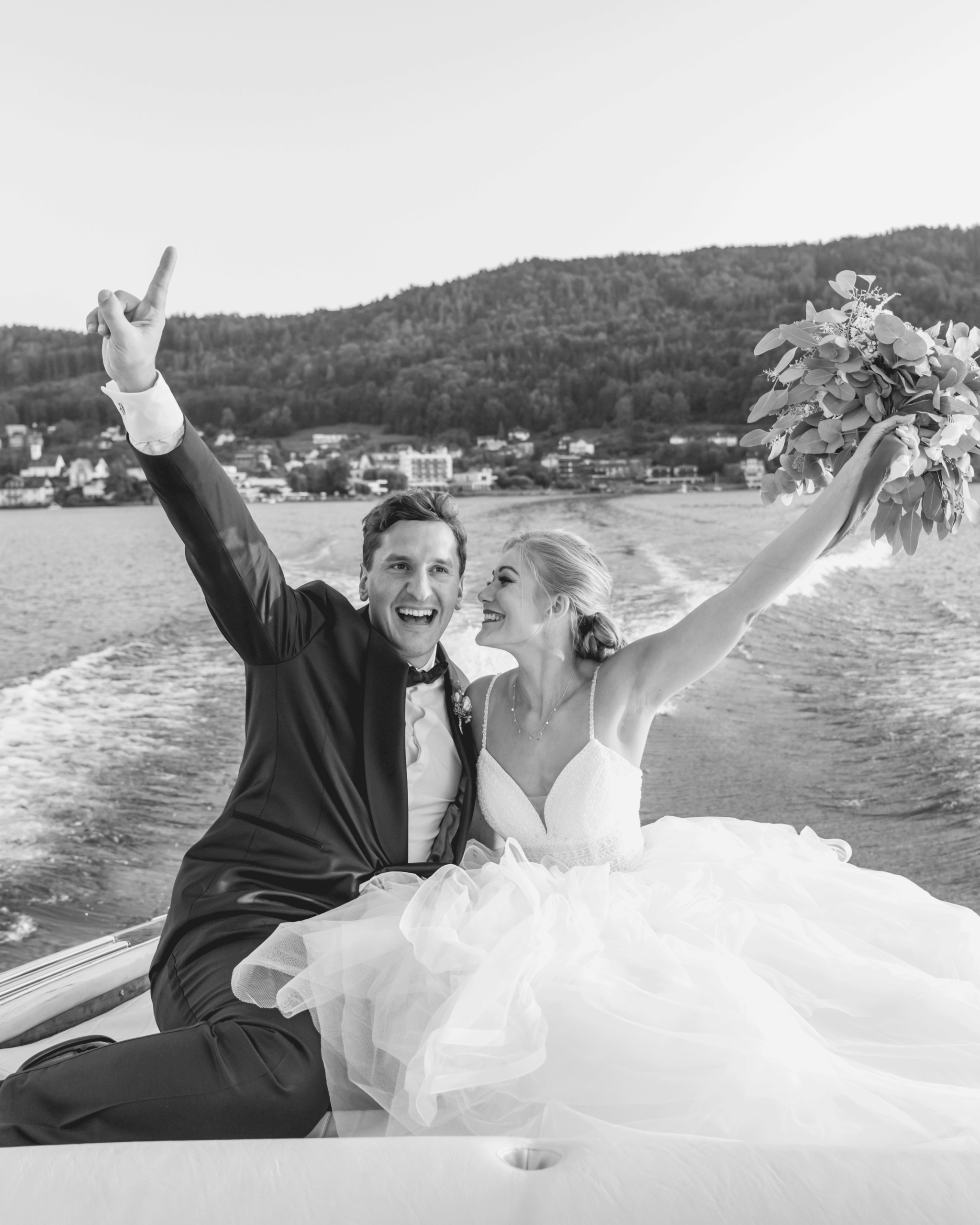 Celebrating bride and groom on a boat, bride holding her bouquet up in the air