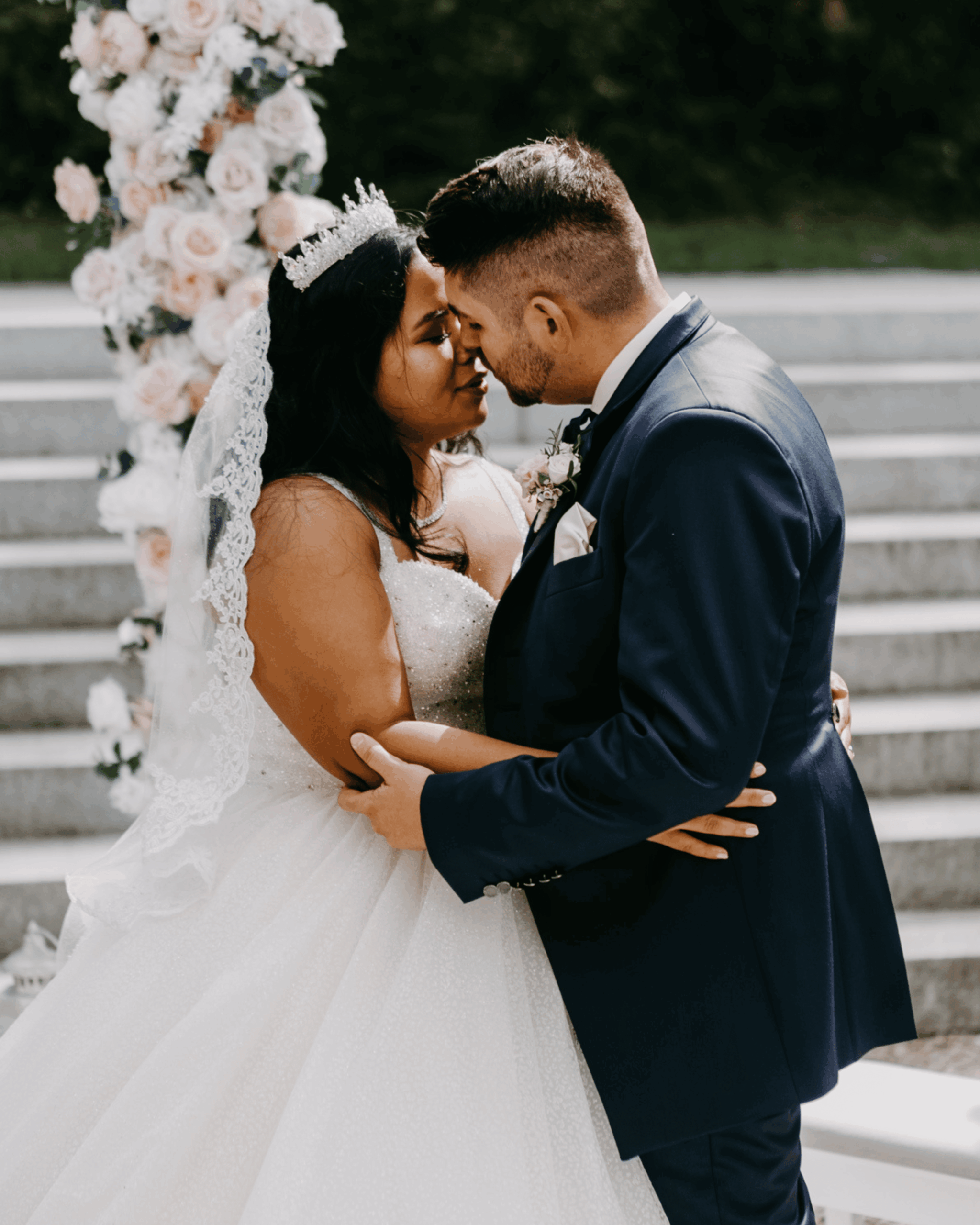 Bridal couple shortly before the kiss at the wedding ceremony, intimate snapshot with floral decoration in the background