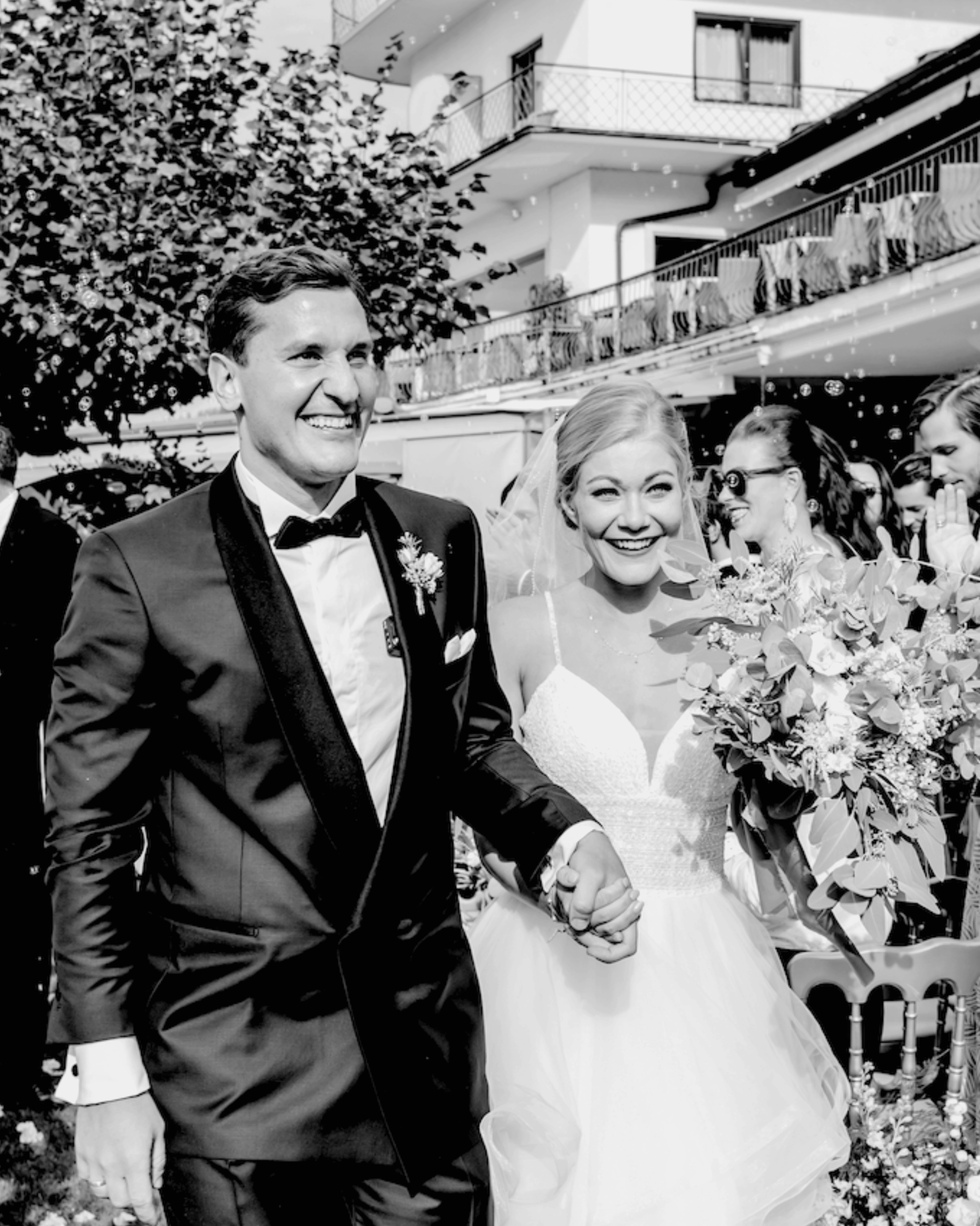 Black and white portrait of a joyful bride and groom leaving the ceremony