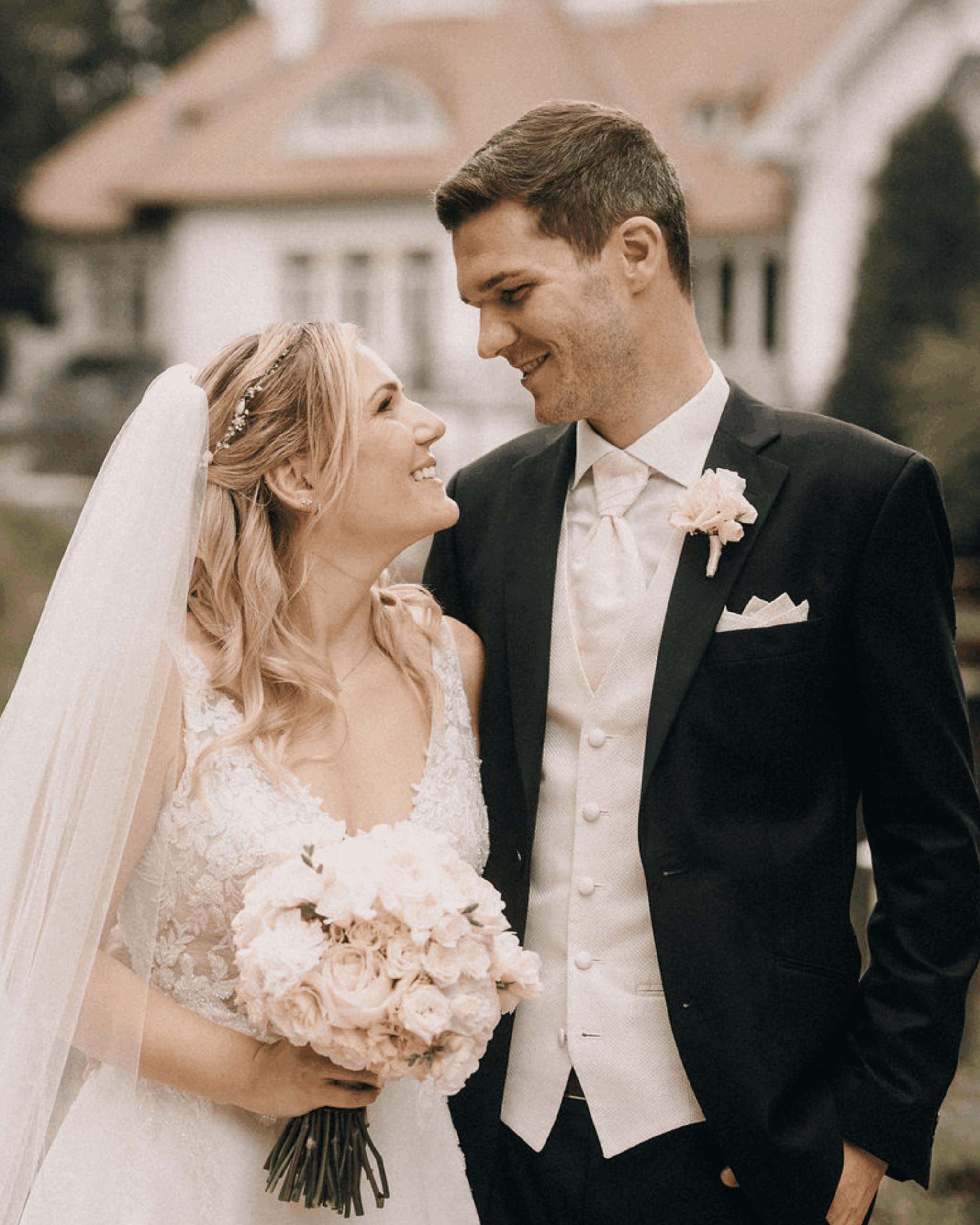 Bride and groom smile at each other, classic wedding portrait against a historical backdrop